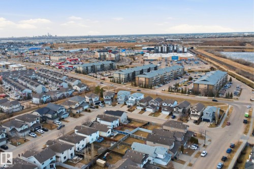 Aerial perspective showcasing residential housing, multi-family buildings, commercial structures, and a distant city skyline under a clear sky - 1144 35 Avenue, Edmonton, AB - Outdoor With View