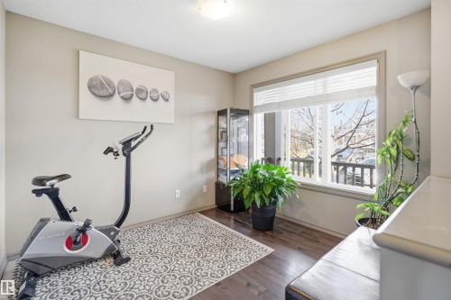 Versatile room featuring neutral wall tones, wood-finish flooring, and a large window with privacy blinds - 1144 35 Avenue, Edmonton, AB - Indoor Photo Showing Gym Room
