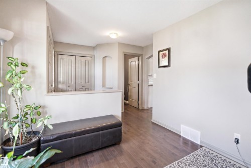 Interior hallway featuring wood-finish flooring, a neutral color palette, bi-fold closet doors, and recessed wall niche - 1144 35 Avenue, Edmonton, AB - Indoor