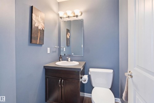 Bathroom featuring a dark wood-finish vanity with an integrated sink, a wall-mounted mirror, and a three-light fixture - 1144 35 Avenue, Edmonton, AB - Indoor Photo Showing Bathroom