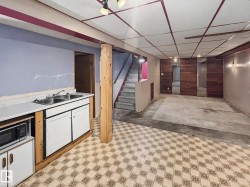 Lower level space featuring a built-in countertop with dual basin sink and white cabinetry - 