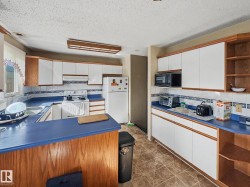 Kitchen featuring white cabinetry with wood-finish trim, blue countertops, and white appliances - 