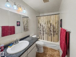 Bathroom featuring a vanity with an oval sink, a wall-mounted mirror, and a bathtub with an overhead shower - 