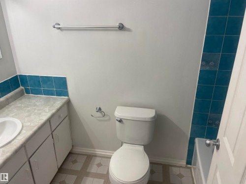 Bathroom featuring a vanity with a white basin and white cabinetry, a toilet, and patterned floor tiles - 2629 129A Avenue, Edmonton, AB - Indoor Photo Showing Bathroom