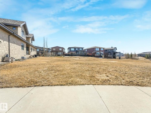Expansive residential lot featuring a concrete sidewalk and partial stone-clad exterior of an adjacent property - 2794 Wheaton Drive, Edmonton, AB 