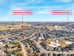 Aerial perspective of a large residential community featuring numerous single-family homes with dark roofing, developed infrastructure including roads, and expanses of open land - 