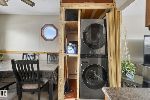 Dedicated laundry area featuring a stacked washer and dryer unit, integrated shelving, and unfinished framing - 2 Scarboro Place, St. Albert, AB - Indoor Photo Showing Laundry Room