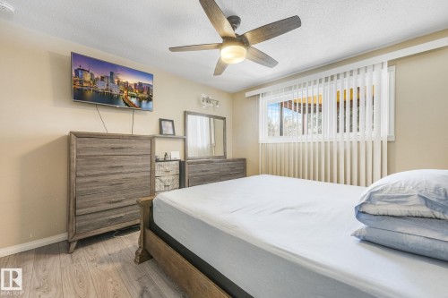 Bedroom featuring light wood-finish flooring, a ceiling fan with integrated lighting, and a window with vertical blinds - 2 Scarboro Place, St. Albert, AB - Indoor Photo Showing Bedroom