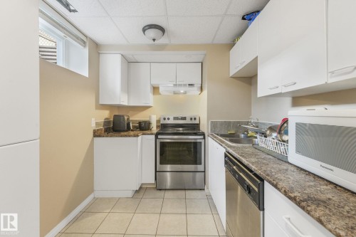 Compact kitchen featuring white cabinetry, stone-finish countertops, stainless steel appliances, and tiled flooring - 2 Scarboro Place, St. Albert, AB - Indoor Photo Showing Kitchen With Double Sink