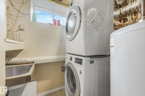 Dedicated laundry area featuring a stacked washer and dryer unit, a utility sink, and overhead shelving - 2 Scarboro Place, St. Albert, AB - Indoor Photo Showing Laundry Room