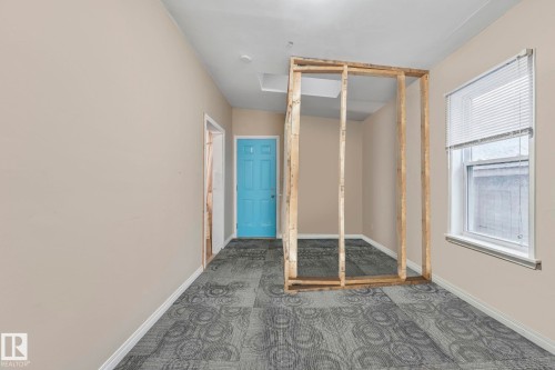Interior space featuring light beige walls, patterned carpet tile flooring, and a bright blue door - 2 Scarboro Place, St. Albert, AB - Indoor Photo Showing Other Room