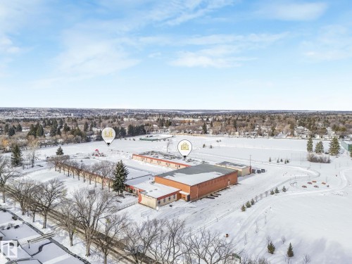 Aerial perspective showcasing the school building, expansive snow-covered grounds, and surrounding treed residential areas under a clear sky - 2 Scarboro Place, St. Albert, AB - Outdoor With View