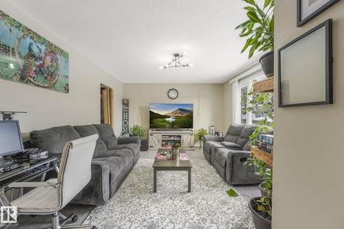 Spacious living area featuring light wood-finish flooring, a contemporary ceiling light fixture, a large window, and light-toned walls - 2 Scarboro Place, St. Albert, AB - Indoor Photo Showing Living Room