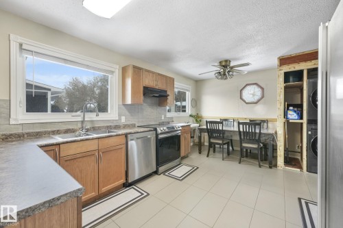 Kitchen featuring tile flooring, wood cabinetry, stainless steel appliances, and a double basin sink - 2 Scarboro Place, St. Albert, AB - Indoor Photo Showing Kitchen