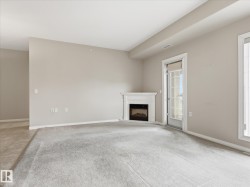 Living area featuring a white mantel fireplace, a glass-paneled exterior door, and light-colored carpeting - 