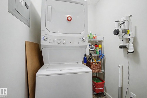 Laundry area featuring a stacked washer and dryer, white walls, and a visible electrical panel - 334 504 Albany Way, Edmonton, AB - Indoor Photo Showing Laundry Room