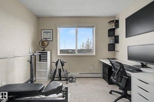 Bright room featuring a large window, neutral wall paint, and light-toned carpet flooring - 334 504 Albany Way, Edmonton, AB - Indoor
