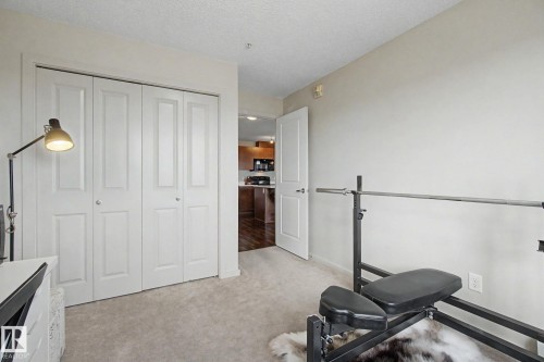 Light-colored carpeting and white walls in a flexible room featuring bi-fold closet doors and a white painted door - 334 504 Albany Way, Edmonton, AB - Indoor