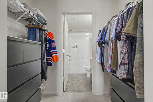 Walk-through closet with built-in dark cabinetry and shelving - 334 504 Albany Way, Edmonton, AB - Indoor With Storage