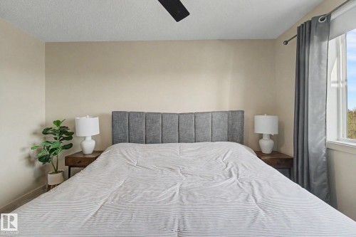 Bedroom featuring light-toned walls, a ceiling fan, and a window with drapery - 334 504 Albany Way, Edmonton, AB - Indoor Photo Showing Bedroom