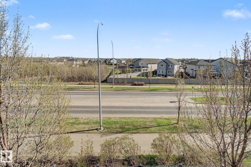 Open skies above a residential neighborhood featuring varied home styles, a multi-lane roadway, and a pedestrian pathway - 334 504 Albany Way, Edmonton, AB - Outdoor With View