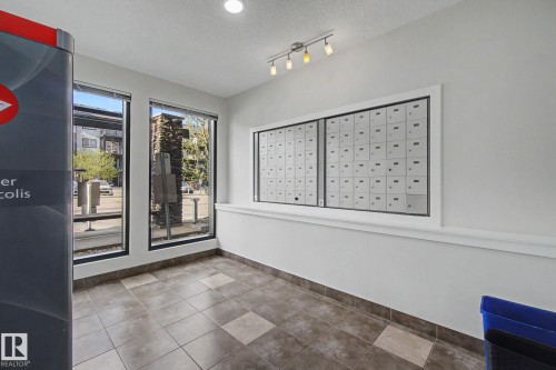 Community mailbox system integrated into a white wall with decorative trim - 334 504 Albany Way, Edmonton, AB - Indoor Photo Showing Other Room