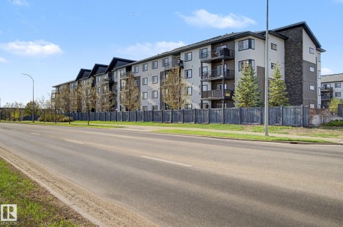 Contemporary apartment building featuring a light-colored stucco facade with dark trim accents and dark stone veneer - 334 504 Albany Way, Edmonton, AB - Outdoor With Balcony With Facade