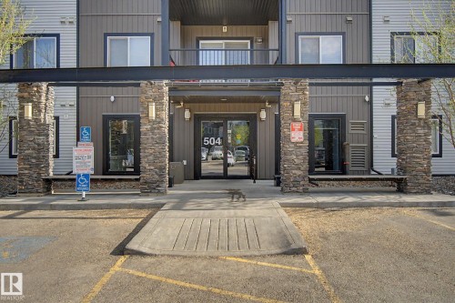 Building exterior featuring stone-clad pillars, a covered entrance, and glass entry doors - 334 504 Albany Way, Edmonton, AB - Outdoor With Balcony