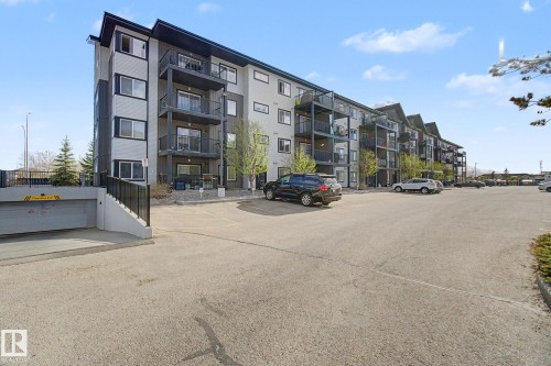 Multi-story residential building featuring a contemporary facade, multiple private balconies, and a surface parking area - 334 504 Albany Way, Edmonton, AB - Outdoor With Balcony