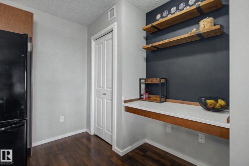 Built-in desk area featuring a light-toned countertop and wood-finish trim, complemented by a dark accent wall - 334 504 Albany Way, Edmonton, AB - Indoor Photo Showing Other Room