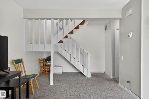 Interior staircase with white painted balusters and wood-finish treads, set against neutral wall tones - 26E Meadowlark Village, Edmonton, AB - Indoor Photo Showing Other Room