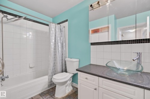 Bathroom featuring a glass vessel sink, dark countertop, and white cabinetry - 26E Meadowlark Village, Edmonton, AB - Indoor Photo Showing Bathroom
