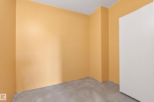 Room featuring light orange walls, a built-in white wardrobe, and concrete flooring - 26E Meadowlark Village, Edmonton, AB - Indoor Photo Showing Other Room