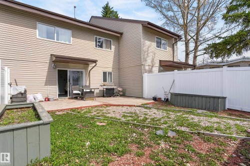 Exterior featuring beige horizontal siding, a private patio area, sliding glass door access, and a white privacy fence - 26E Meadowlark Village, Edmonton, AB - Outdoor With Exterior