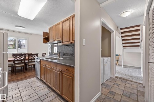 Kitchen featuring wood cabinetry, a stainless steel dishwasher, and a dark countertop with an undermount sink - 26E Meadowlark Village, Edmonton, AB - Indoor Photo Showing Kitchen With Double Sink