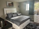 Bedroom featuring light-toned walls, a white tufted headboard, and wood-finish flooring - 204 10811 115 Street, Edmonton, AB  - Indoor Photo Showing Bedroom 