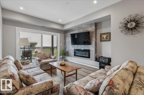 ELECTRIC LINEAR FIREPLACE WITH TILE SURROUND, PATIO WITH SPECTACULAR RAVINE AND DOWNTOWN VIEWS - 428 7463 May Common, Edmonton, AB - Indoor Photo Showing Living Room With Fireplace
