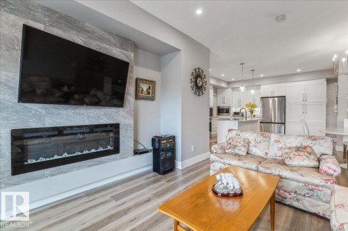LUXURY VINYL PLANK FLOORING THROUGHT THE LIVING ROOM, KITCHEN, DINING ROOM, LAUNDRY ROOM AND ENTRANCE - 428 7463 May Common, Edmonton, AB - Indoor Photo Showing Living Room With Fireplace