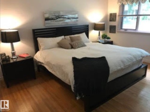 Hardwood-style flooring throughout, featuring a window with a valance, and a built-in headboard - 9126 117 Street, Edmonton, AB 