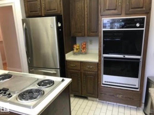 Kitchen featuring dark wood cabinetry, a stainless steel refrigerator, and a built-in double oven - 9126 117 Street, Edmonton, AB 