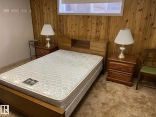 Room with wood paneling accent wall, a window, and carpeted flooring - 9126 117 Street, Edmonton, AB 