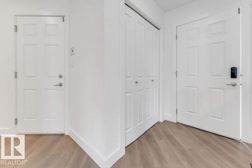 Light wood-finish flooring complements white walls and trim throughout - 7403 Singer Landing Landing, Edmonton, AB - Indoor Photo Showing Other Room
