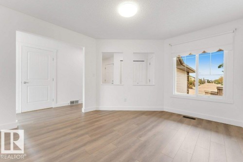 Spacious room featuring wood-finish flooring and a large bay window - 7403 Singer Landing Landing, Edmonton, AB - Indoor Photo Showing Other Room