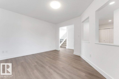 Open concept living space featuring wood-finish flooring, bright white walls, and recessed lighting - 7403 Singer Landing Landing, Edmonton, AB - Indoor Photo Showing Other Room