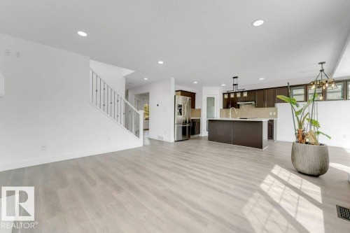Expansive open-concept living space featuring light wood-finish flooring, recessed lighting, and a contemporary staircase with white balusters - 7403 Singer Landing Landing, Edmonton, AB - Indoor Photo Showing Kitchen