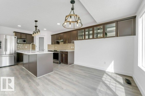 Open-concept kitchen featuring an island with an undermount sink and gooseneck faucet - 7403 Singer Landing Landing, Edmonton, AB - Indoor Photo Showing Kitchen With Upgraded Kitchen