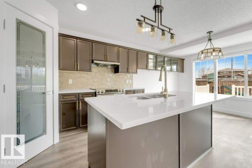Expansive kitchen island featuring a light-toned countertop and integrated sink - 7403 Singer Landing Landing, Edmonton, AB - Indoor Photo Showing Kitchen With Double Sink With Upgraded Kitchen