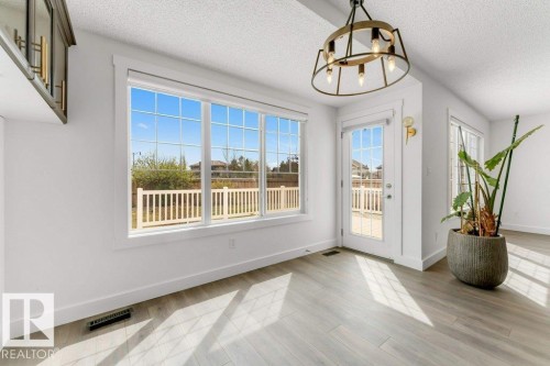 Bright interior space featuring a large picture window, a glass-paned door, and wood-finish flooring - 7403 Singer Landing Landing, Edmonton, AB - Indoor Photo Showing Other Room