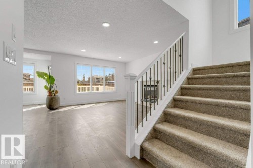 Carpeted staircase with white newel posts and black iron balusters - 7403 Singer Landing Landing, Edmonton, AB - Indoor Photo Showing Other Room