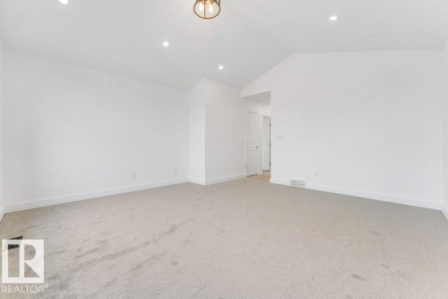 Spacious room featuring vaulted ceilings, recessed lighting, neutral carpeting, and a contemporary ceiling fixture - 7403 Singer Landing Landing, Edmonton, AB - Indoor Photo Showing Other Room